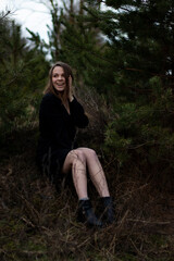 Naklejka premium young brunette woman with short hair in a black dress near the pines