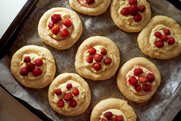 Homemade baking. Buns with cottage cheese and berries on a baking sheet