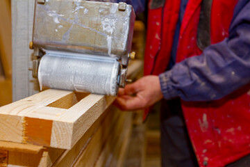 Carpenter smears the boards with hand roller tool, spreader for evenly application of glue on the wooden surface