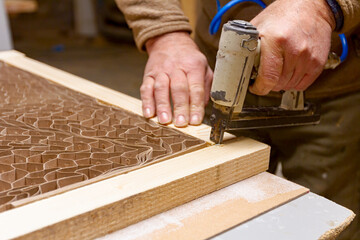 Carpenter assembles boards on the door frame with pneumatic stapler