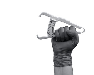 A caliper for measuring subcutaneous fat, in the hand compressed into a fist in a rubber glove,...