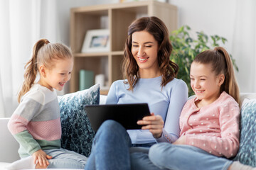 people, family and technology concept - happy mother and two daughters with tablet pc computer at home