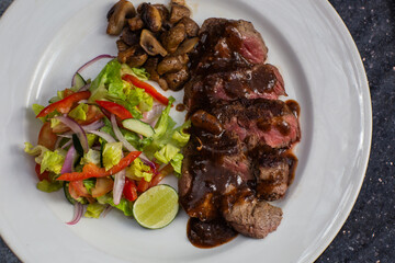 Juicy beef tenderloin steak sliced on a plate with vegetable salad