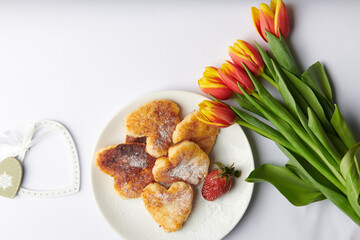  hearts next to a plate with heart shaped cheesecakes and a bouquet of tulips 