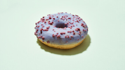 Donut recipe everyone loves. Freshly baked delicious donut with colorful sprinkles and purple sugar glaze isolated on light background