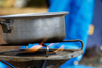 saucepan with water heated on a gas stove when camping: boiling water for cooking food in a container on a portable gas heater in front of a tent