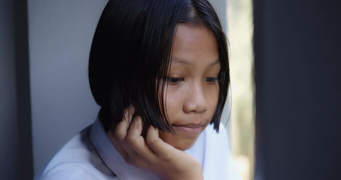A native Asian black girl who started out as a teenage girl. There are pimples on her face and forehead and thinking, absent-minded, depressed, looked out of the window.