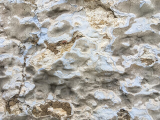 rough stone wall with cracked blue, gray and white paint and cement