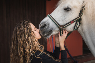 Young caucasian woman kissing a horse