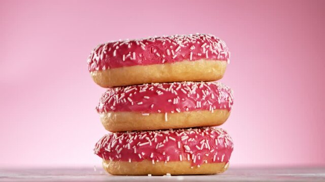 Delicious donuts falls on pastel background. Super Slow motion