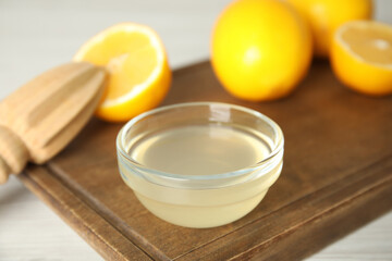 Fototapeta na wymiar Freshly squeezed lemon juice in bowl on wooden board, closeup