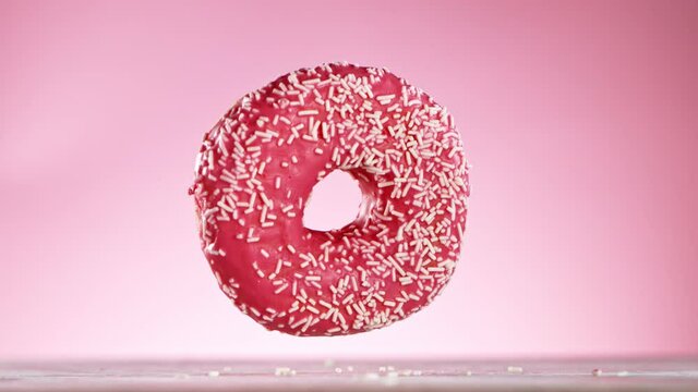 Delicious donut falls on pastel background. Super Slow motion