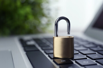 Metal padlock on laptop keyboard, space for text. Cyber security concept