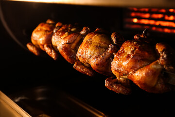 Grilling whole chickens in rotisserie machine, closeup