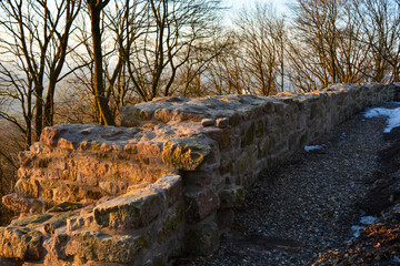 Steinmauer mit Schnee und Sonnenlicht im Winter am Zabelstein in Franken