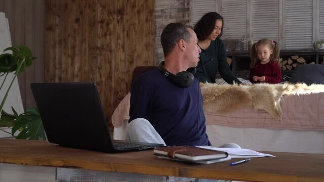 Parent Works from Home with Kids during COVID-19 Lockdowns. Remote working with a family. Online chat. Father works remotely, mother and little daughter play noisily