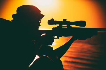 Commando team sniper, army special forces shooter aiming, shooting sniper rifle while sitting on...