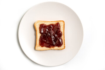 Slice of toasted bread with red strawberry jam in a white plate isolated on white background - top view