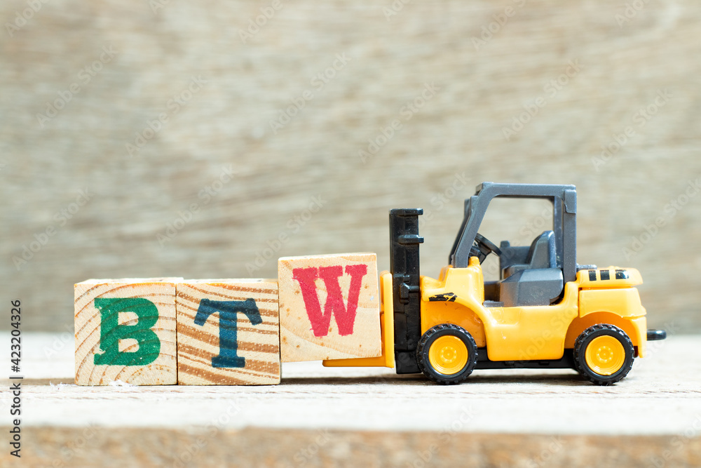 Wall mural toy forklift hold letter block w to complete word btw (abbreviation of by the way) on wood backgroun