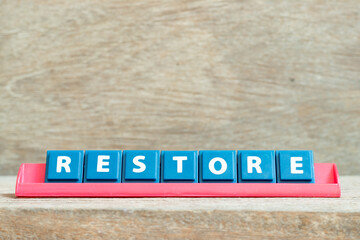 Tile alphabet letter with word restore in red color rack on wood background