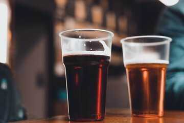Two glasses of dark and light beer on a table in a pub, close-up. Selective focus, blur
