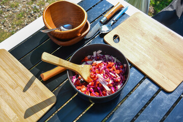 Camping kitchen on the camping table, with pot with vegetables, cooking spoon, cutlery and wooden...