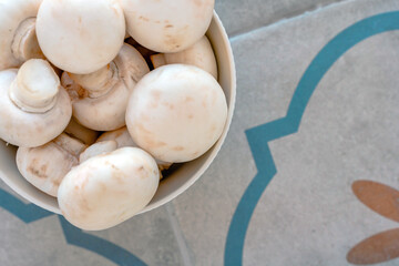A bowl of fresh mushrooms on a beautiful ceramic tile