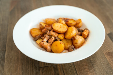 Potatoes with meat and mushrooms on a white plate