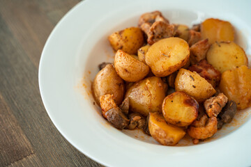 Potatoes with meat and mushrooms on a white plate