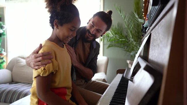 Happy father playing piano with daughter at home