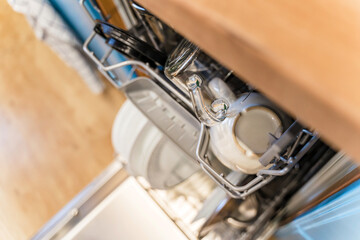 Obraz premium Clean dishes in the open dishwasher in the kitchen with light blue facades