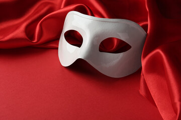 White theatre mask and fabric on red background
