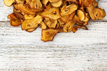 A pile of dried pears in slices on a white wooden background. Dried fruit chips. Healthy food