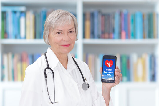 Friendly senior doctor with a smartphone showing a blood pressure diary app, mobile health concept.
