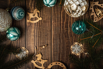 New Year's decor on a wooden background. Fir branches, Christmas balls and wooden toys. Cozy home. Place for the text. View from above