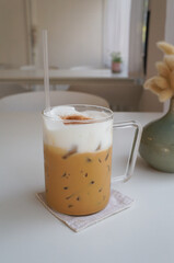 Ice coffee on white table with cream being poured into it showing the texture and refreshing look of the drink, with a clean background.