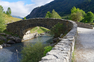 Fototapeta na wymiar small stone bridge over a stream in front of the Pyrenees mountains in Gavarnie