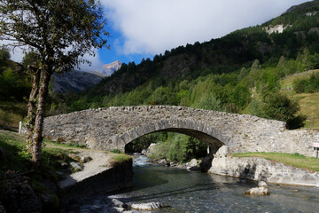 Fototapeta na wymiar small stone bridge over a stream in front of the Pyrenees mountains in Gavarnie
