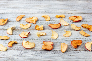 Obraz na płótnie Canvas Pattern of a pile of dried apples in slices on a white wooden background. Dried fruit chips. Healthy food