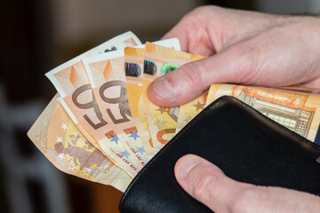 mani che prendono i soldi dal portafogli