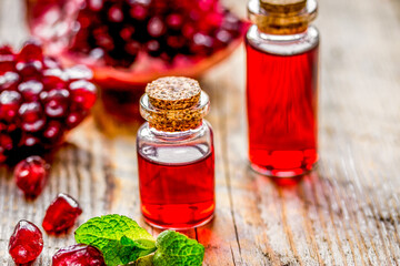 sliced pomegranate and extract in glass on wooden background
