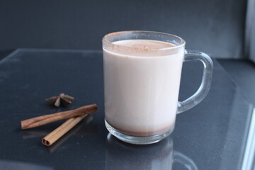 cocoa hot chocolate in a glass mug with cinnamon sticks and badyan on a black background with a place to text a copyspace