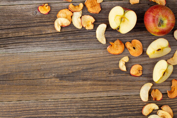 A pile of dried slices of apples and fresh ripe apples on wooden background.
