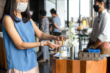 Woman wear face mask pressing alcohol gel cleaning her hand for COVID-19.