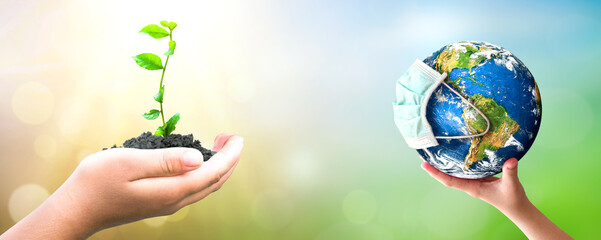 Earth Day concept: hand holding  plant and earth on blur green nature background
