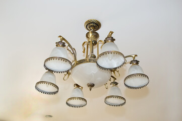 close-up - a beautiful chandelier with a bronze frame and white marble shades