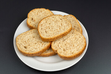 bread dried in the oven on a white ceramic plate on a black background