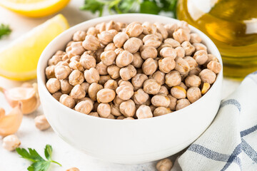 Chickpeas in white bowl at light kitchen table.