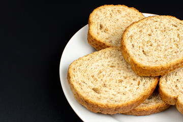 bread dried in the oven on a white ceramic plate on a black background