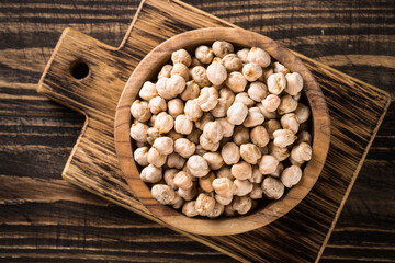 Chickpeas in white bowl at wooden kitchen table.